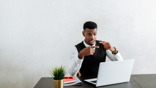 a man sitting at a table with a computer talking