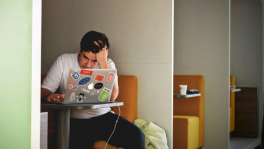 man siting at table using macbook