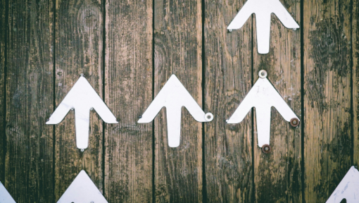 white arrows on a wood wall pointing up